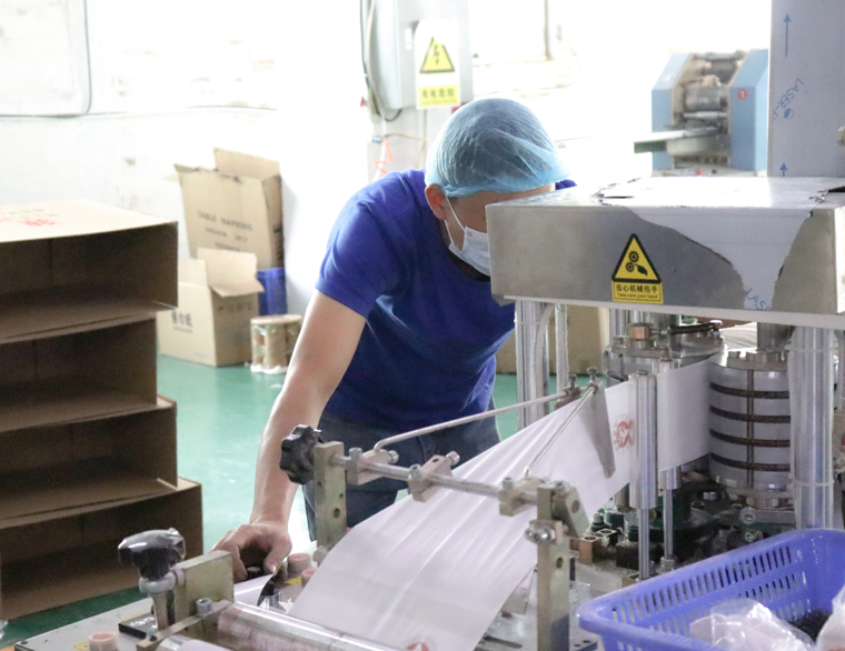 Trabajador de control de calidad inspeccionando el proceso de producción de papel higiénico.